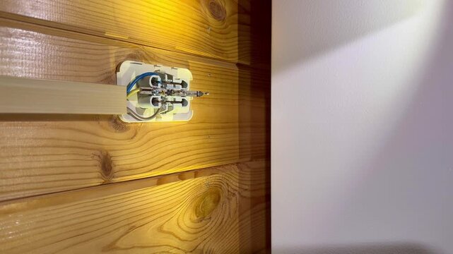 Surface mounted electrical socket base fixed on wooden wall inside residential room.