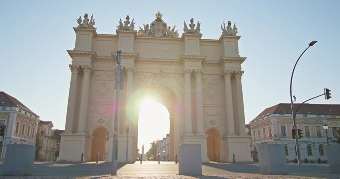 Potsdam, Germany: Brandenburg Gate forms a neoclassical landmark at Luisenplatz, with low sun shining through the central arch.