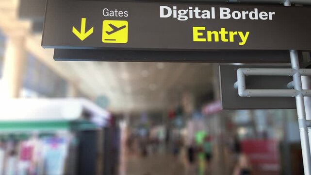 Airport sign indicating the direction to the gates and the digital border entry, with travelers walking in the blurred background. Biometric technology is improving security and streamlining travel