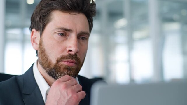 Serious Caucasian middle-aged business man working with laptop thinking holding chin pondering project developing idea businessman pensive think with computer technology ponder strategy plan in office