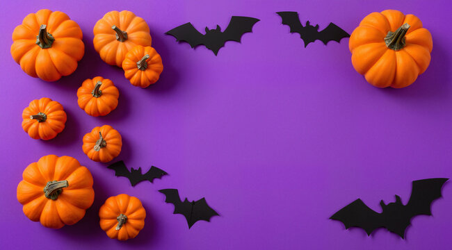 Top view photo of halloween decorations small pumpkins and bats silhouettes on isolated violet background with empty space

