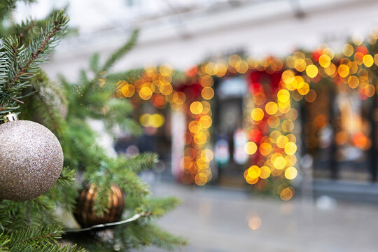 Pine branch with glitter ornament. Warm golden bokeh background. Festive storefront decoration. Winter holiday atmosphere. Background for New Year's or Christmas greetings. Copy space