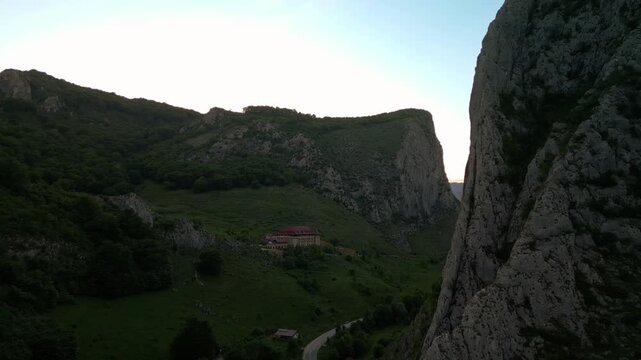 Mountain valley with winding road and building at sunset