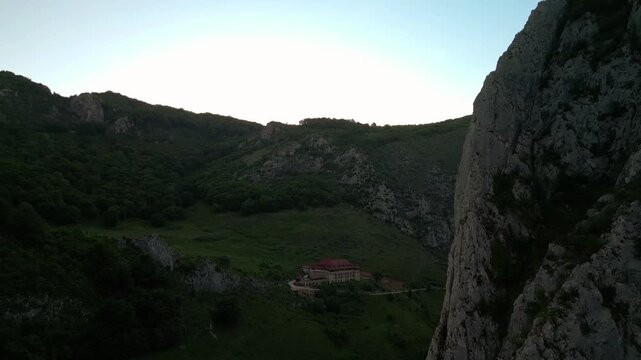 Hotel building resting in a valley with forested hills and steep rocky mountainsides