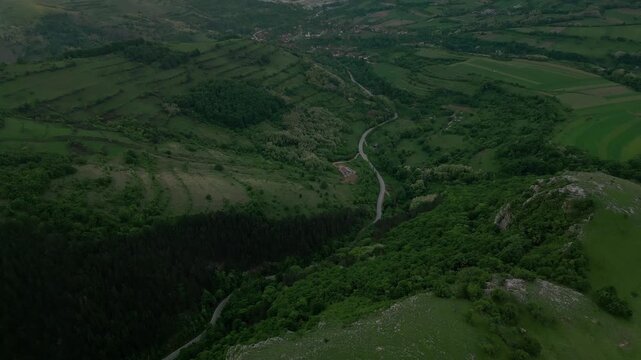 Aerial view winding road through green valley hills