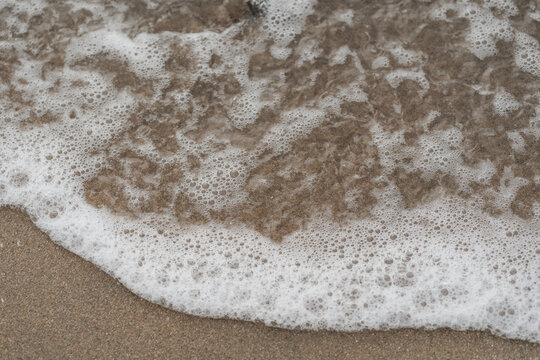 Espuma de mar densa cubriendo la arena en primer plano