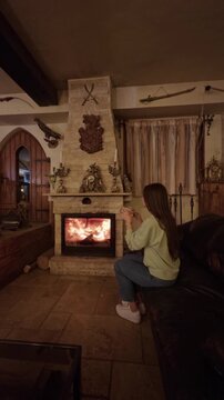 Young girl relaxing by cozy fireplace at home