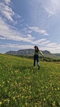 Woman running through spring meadow feeling freedom
