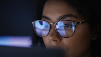Fototapeta premium Woman Focused on Computer Screen with Glasses Reflection at Night
