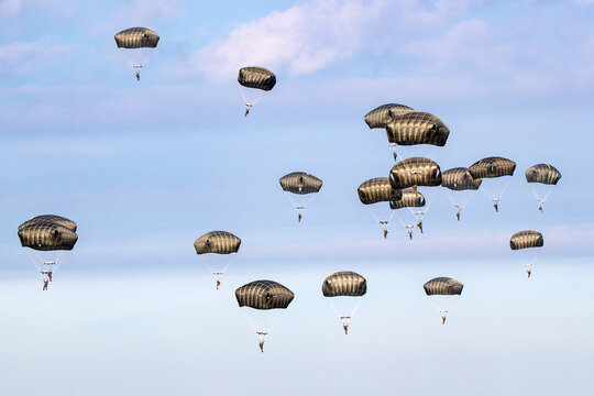 Military parachutist paratroopers parachute jumping out of an air force plane.