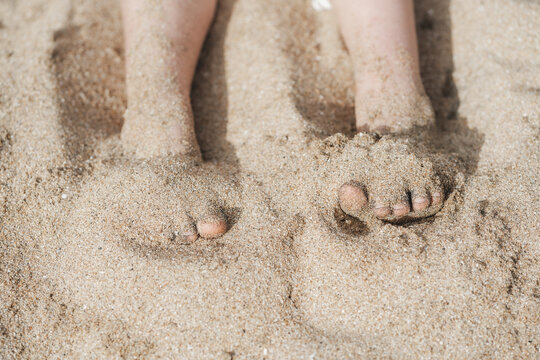 Pies peque&ntilde;os hundidos en la arena de playa