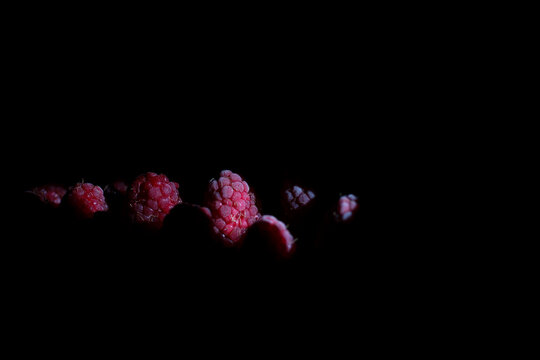 Fresh raspberries in dramatic light with copy space
