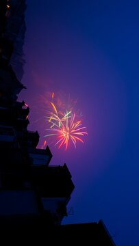 Colorful Fireworks Explode Over Silhouetted Buildings at Dusk