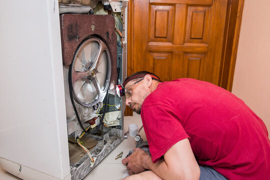 The man is repairing the washing machine.