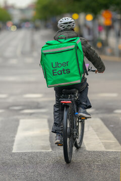 Gothenburg, Sweden - July 28 2026: Uber Eats cyclist delivering food along wet city street.
