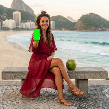 Mulher segurando celular tela verde mockup na praia rio de janeiro 