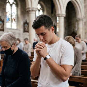 Homem rezando na missa na igreja cat&oacute;lica