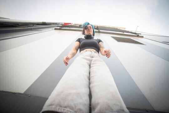  Symmetric low angle shot of confident gen z alternative woman with blue hair and copy space