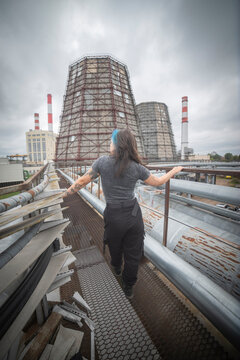  Alternative gen z woman exploring heavy industrial power plant infrastructure with copy space