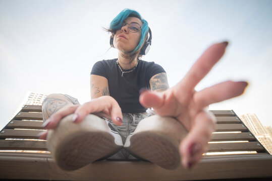 Trendy gen z woman with blue hair and headphones looking at camera with copy space