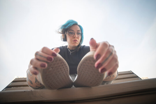 Cool gen z alternative woman with blue hair holding her shoes with copy space