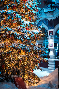 Festive Snow-Covered Christmas Tree With Warm Lights and Red Ornaments Outside