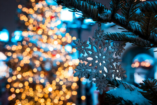 Sparkling Snowflake Ornament Hanging On Christmas Tree With Warm Bokeh Holiday Lights