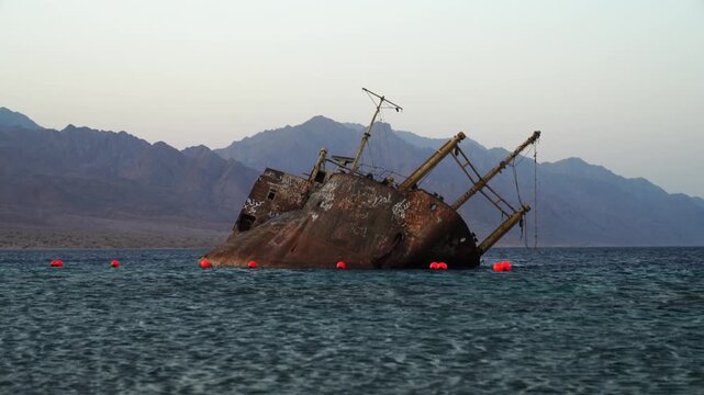 Cinematic view of the historic Georgios G shipwreck stranded in shallow turquoise waters along the Red Sea coast in Haql, Tabuk