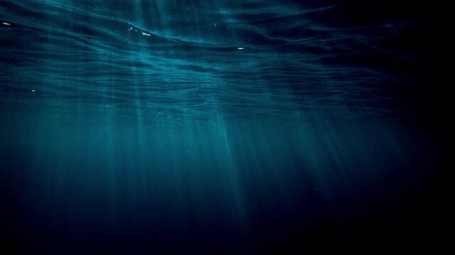 Ocean blue underwater with sunrays, Underwater Sea Deep Water Abstract Sunshine, sea wave , clean waters in summer time, Natural underwater seascape, sand on ocean floor and water surface sunlight.
