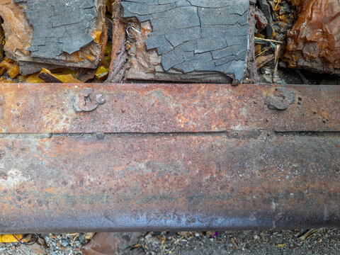A completely rusted iron texture, topped with a piece of rubberwood that has partially turned into charcoal