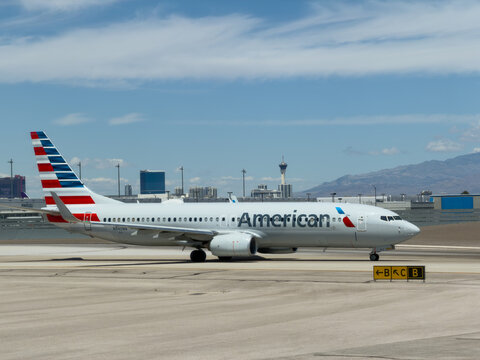 LAS VEGAS, NV, APR 28, 2026: American Airlines 737 taxiing past a directional sign, with the Las Vegas skyline and mountains in the distance