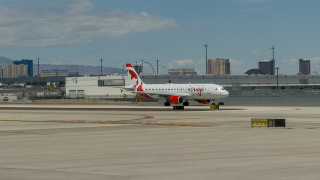 LAS VEGAS, NV, APR 28, 2026: Air Canada Rouge jet taxiing on the ramp with the Las Vegas Strip skyline and cargo center building behind it