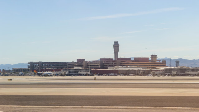 LAS VEGAS, NV, APR 28, 2026: Distant view of an airport terminal with control towers, jet bridges, and parked planes across a wide runway, Harry Reid International Airport