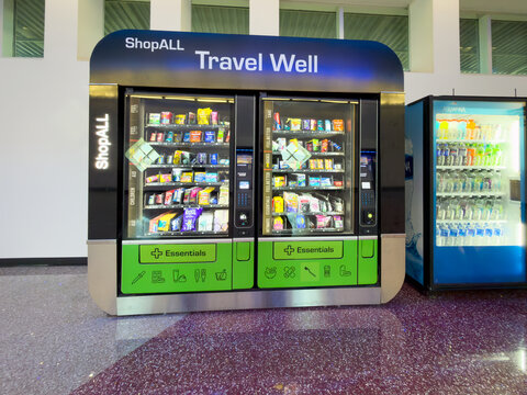 LAS VEGAS, NV, APR 28, 2026: ShopALL "Travel Well" double vending kiosk stocked with medicine and essentials, next to an Aquafina beverage cooler in airport terminal
