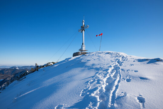 Metal summit cross and wind vane on the snow-covered Wallberg summit.