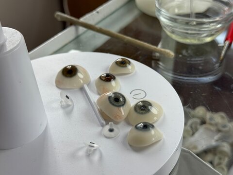 Realistic artificial eyes displayed on a white rotating stand in workshop