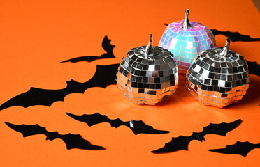 Naklejka premium halloween party decoration with black paper bats and shiny disco ball ornaments on orange background