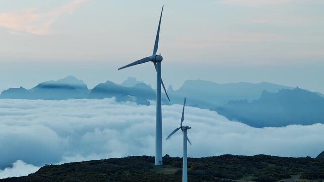 Wind turbines on ridge with cloud inversion below, renewable energy landscape in Madeira, Portugal