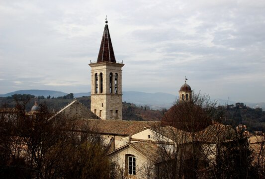 SPOLETO, ITALY - FEBRUARY 7, 2017: Bell tower and dome of the Spoleto Cathedral. Sitting on the slopes of Monte Luco, the tower features multi-level arched windows and a dark, pointed conical roof