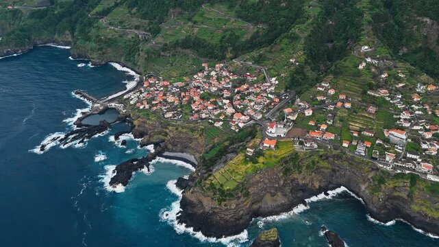 Seixal village along volcanic coast of Madeira, Portugal. Elevated aerial view of settlement between ocean coves and cultivated hillsides