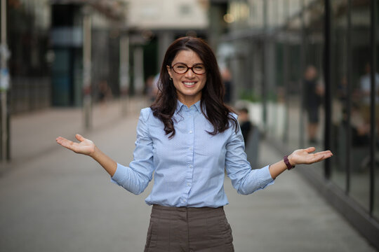 Smiling businesswoman presenting with open hands urban street