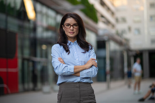 Confident business woman standing with crossed arms in city