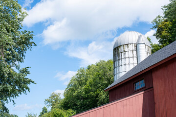 Red barn with metal silo on a farm on sunny day © Maxwell