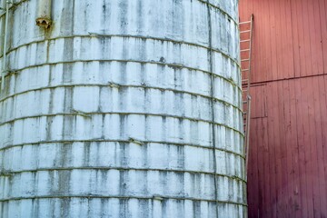 Concrete silo next to red wooden barn with metal ladder © Maxwell