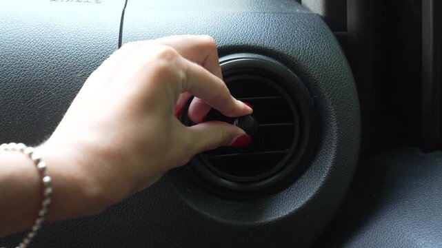 Horizontal video of a woman's hand adjusting the air vent inside a car, controlling the direction of airflow while driving