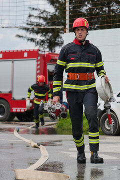 Firefighters Carrying Hoses and Equipment Beside Red Fire Truck During Emergency Response