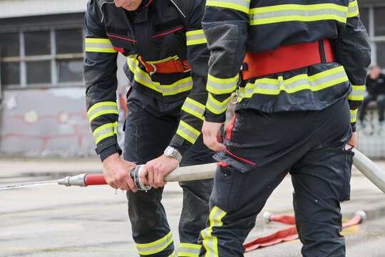 Firefighters Teamwork Connecting Fire Hose During Outdoor Emergency Training Drill
