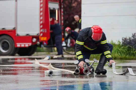 Firefighter Kneeling to Connect Hoses at Fire Truck During Emergency Response Training