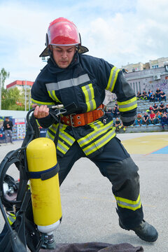 Firefighter Putting On Breathing Apparatus During Urban Training Drill With Yellow Oxygen Cylinder