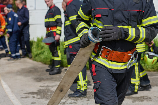 Firefighter Holding Fire Hose During Emergency Response Drill With Team In Protective Gear